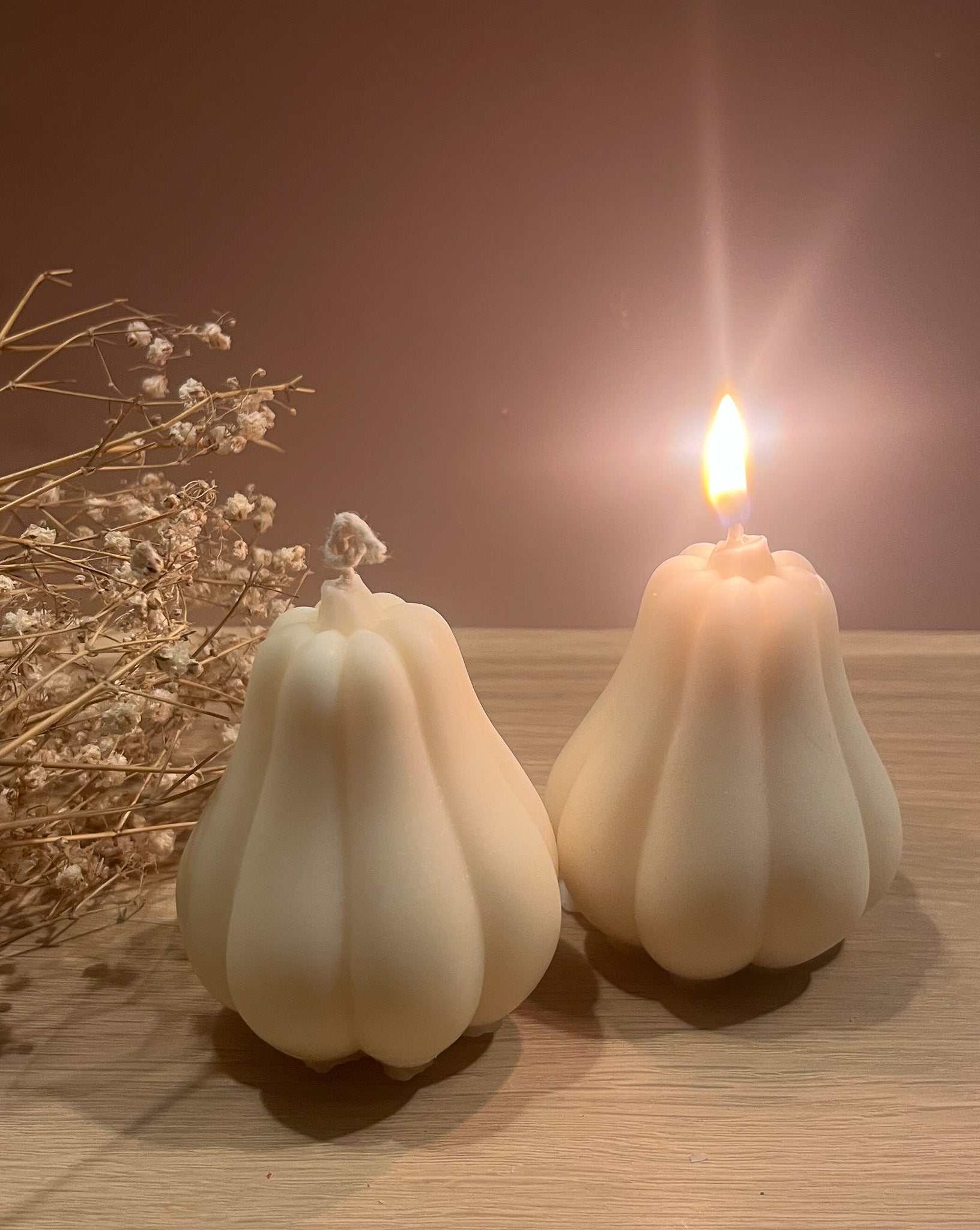 To butternut græskar sojalys, hvor det ene brænder og spreder en rolig, varm glød.