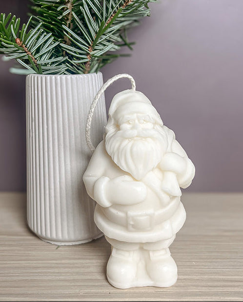 Håndlavet julemand sojalys foran en lille vase med gran – naturlig og hyggelig juledekoration i sojavoks.