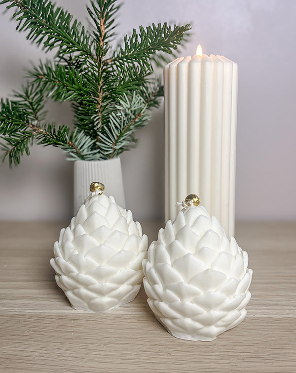 To kogle sojalys foran vase med gran og bloklys – naturlig og hyggelig vinterpynt i dæmpede nuancer.