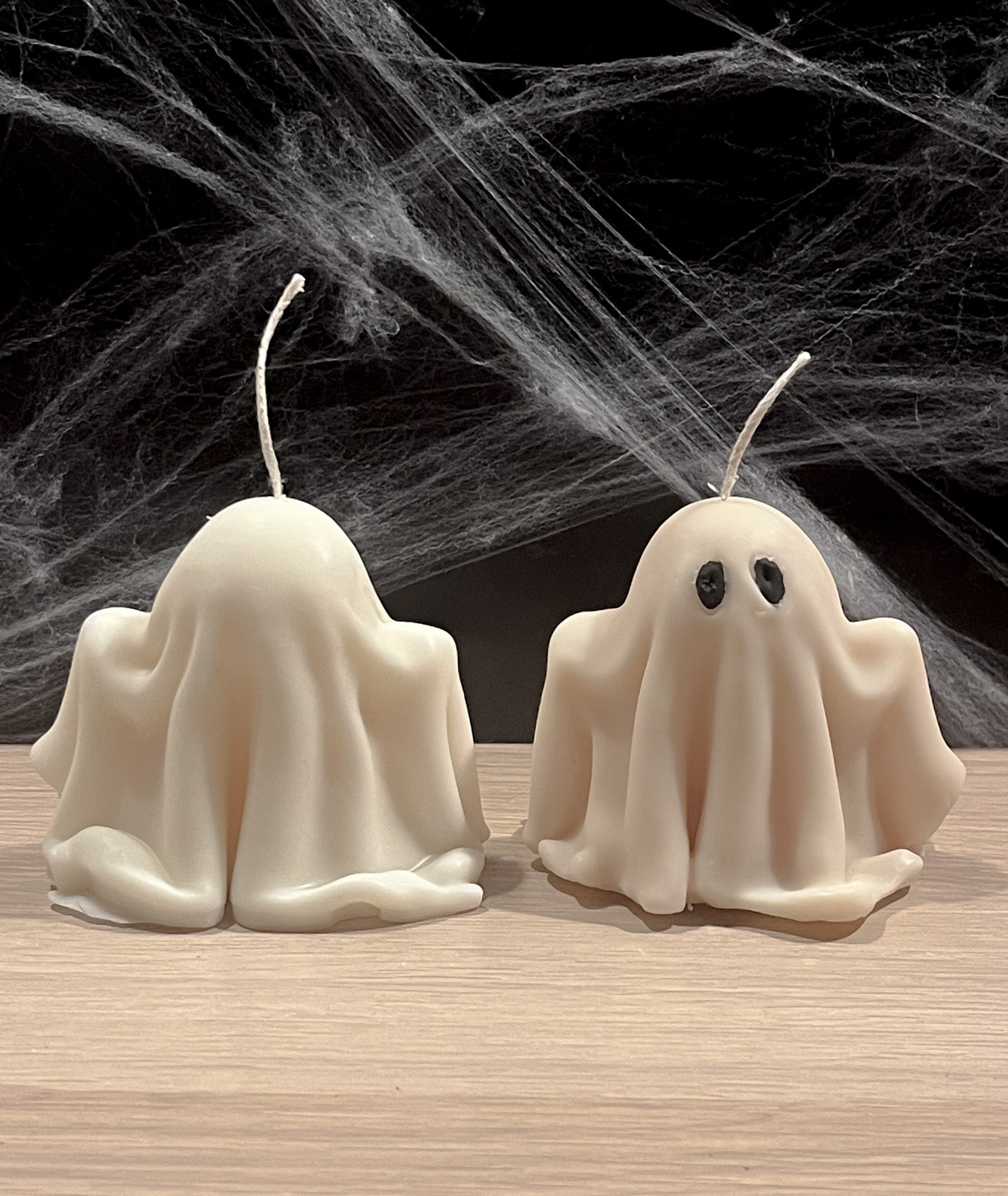 To håndstøbte spøgelses sojalys i hvid sojavoks, hvor det ene ses bagfra og viser de glatte, håndlavede former.