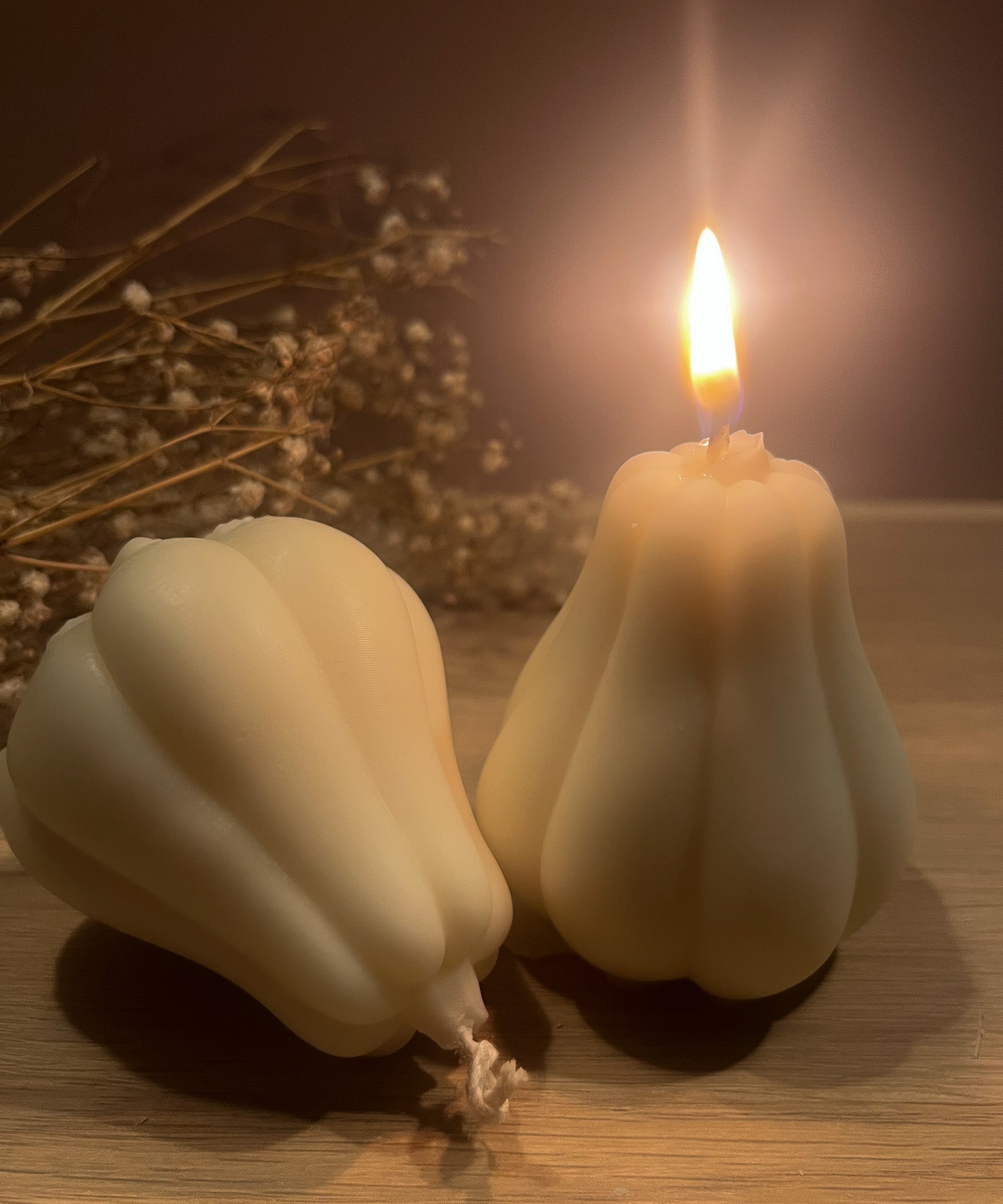 To butternut græskar sojalys, hvor det ene er tændt og det andet ligger ned. Skaber en varm og hyggelig stemning.