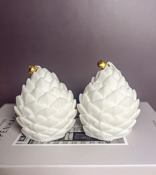 To håndlavede koglelys i sojavoks placeret oven på en bog – enkel og naturlig dekoration med vinterstemning.