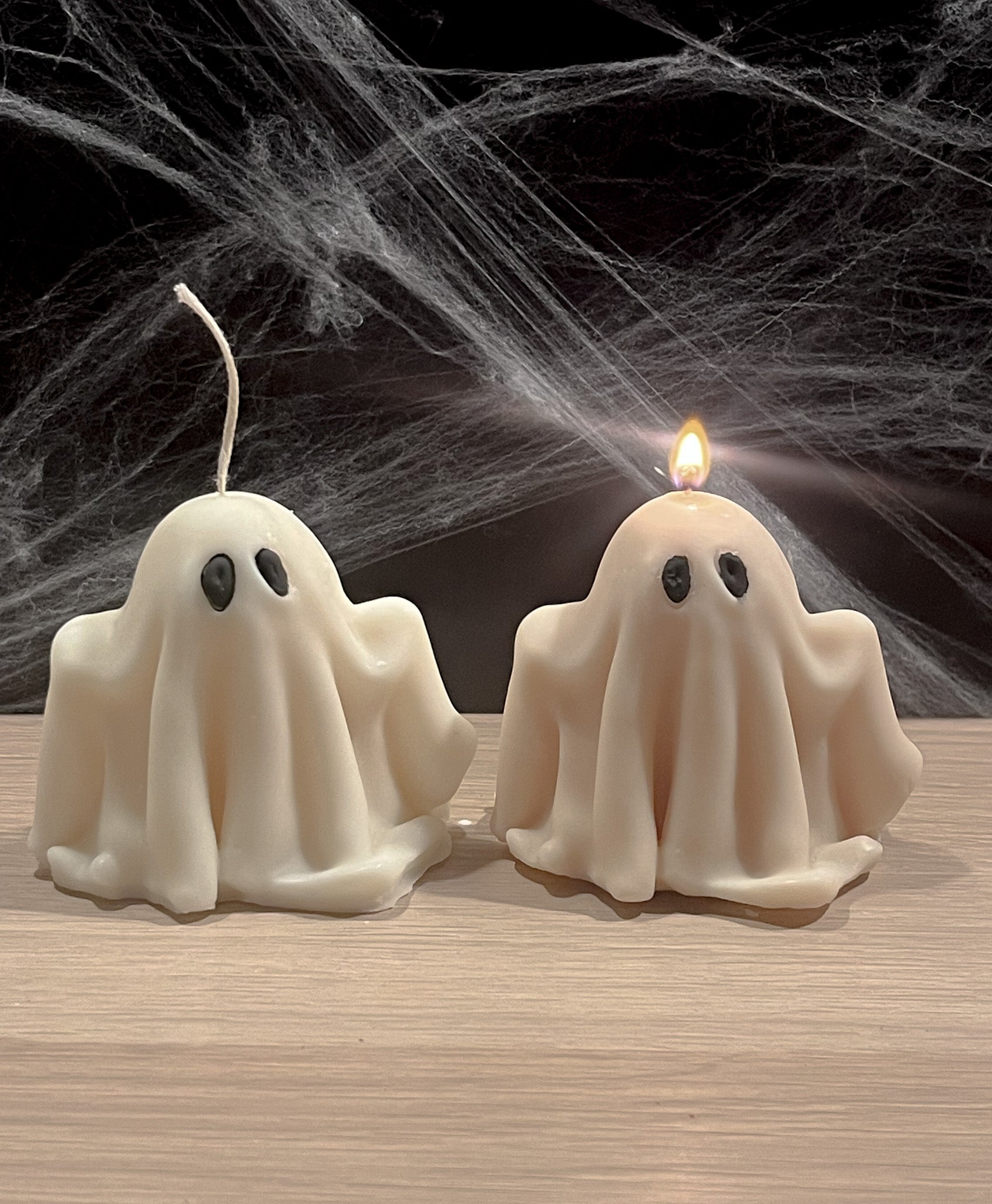 To håndlavede spøgelseslys i sojavoks, hvor det ene er tændt og spreder varm, (u)hyggelig efterårsstemning.