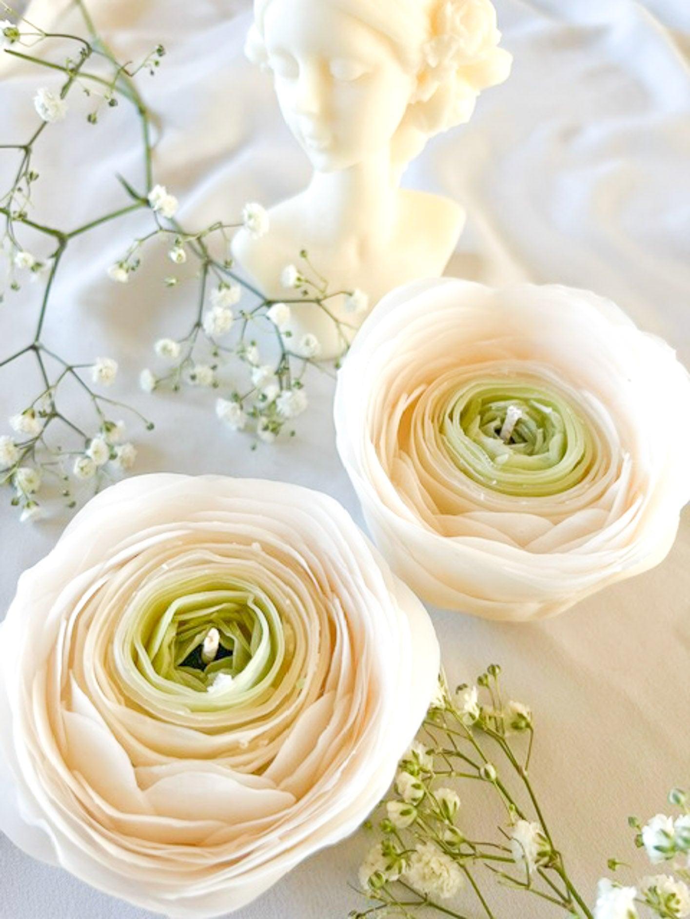 Stemningsfulgt billede af smukke hvide ranunkel blomsterlys håndmodelleret af ren bivoks for en renere brænding.