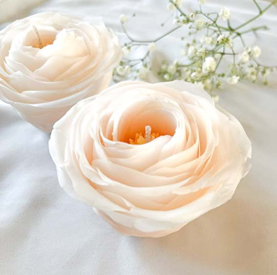 Close up så man kan se et hvidt blomsterlys formet som en hvid rose med et orange center.